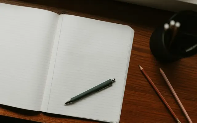 Open notebook with a pen and pencils